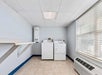 Laundry room with a washing machine and dryer next to a window. Shelves are mounted on the left wall, and a vent is below the window. The floor is tiled, and the walls are painted light blue.