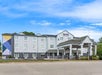 Three-story hotel with a light grey exterior, triangular roof, and a covered entrance. It has a sign reading "spark" at the top and a mural on the side. A parking lot surrounds the building.