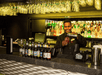 A bar tender standing behind the bar pouring a drink with a line of beers on the counter in front of him on the Spirit of New York Signature Dinner Cruise.