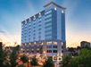 View of the front and side exterior of the SpringHill Suites by Marriott Atlanta Downtown at dusk with the sun setting behind it.