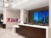 A lobby with a modern white and brown front desk with three computers at it and a deep blue photo on the wall behind it.