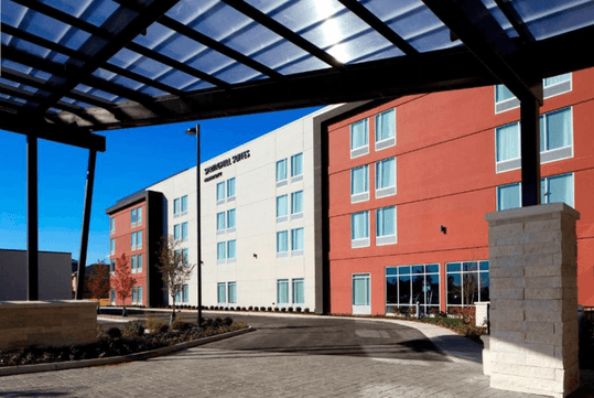 View looking up at the red, white, and black exterior of the SpringHill Suites by Marriott on a sunny day in Columbus, Ohio.
