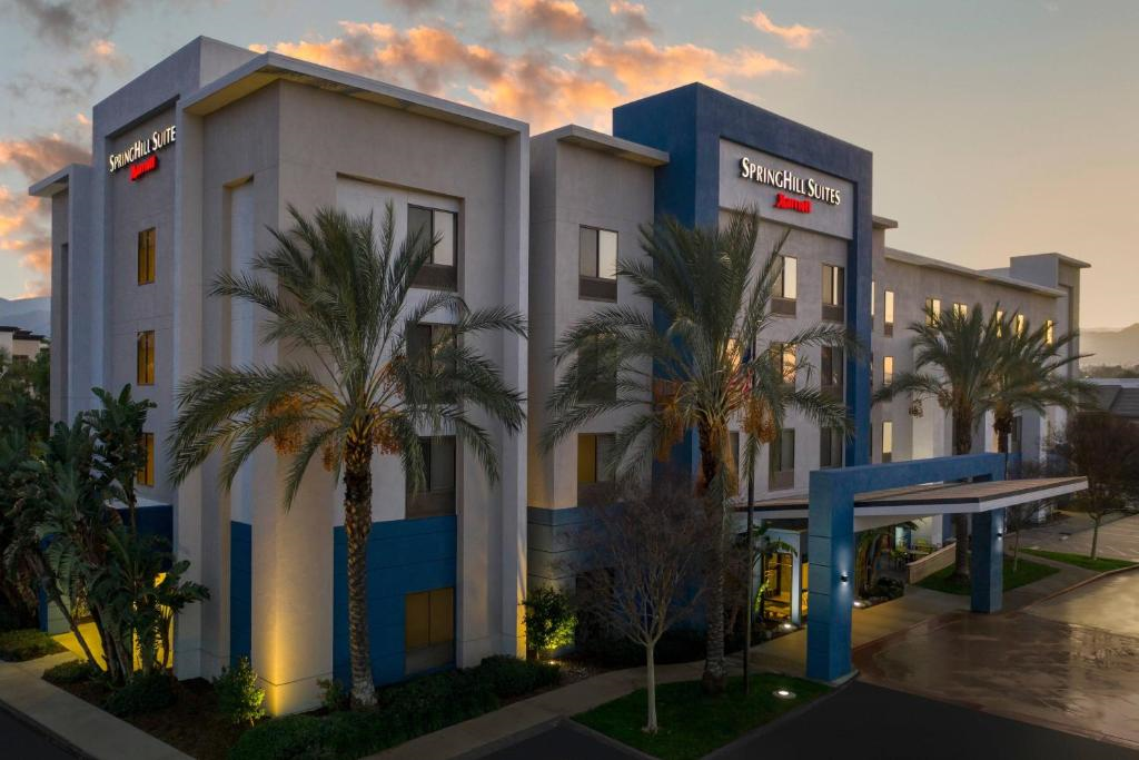 A SpringHill Suites hotel building with palm trees in front, illuminated at dusk.