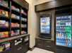 A small market area with brown shelves stuffed full of snack on the left and refrigerators full of drinks and food on the right.