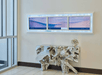 An abstract silver buffet table with light purple art above it and glass doors to its left in the lobby of the SpringHill Suites Denver Downtown.