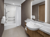 Modern bathroom with a bathtub and shower, white curtain, large mirror, sink, and wooden cabinetry. Brown walls and tiled floor complete the clean, minimalist design.