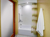 A bathroom with a bathtub, a wall-mounted shower, a striped shower curtain, and a towel hanging on a rack.