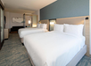 Hotel room with two large beds, modern decor, a seating area, and soft lighting.