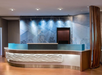 Modern hotel reception desk with wave-patterned front, blue accents, and wall text design in the background.