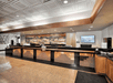 Hotel reception area with a long counter. The ceiling has a patterned design, and a large mural decorates the back wall. A screen displays an image on the right side.