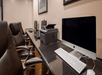 Office with leather chairs, computers, a printer, and a framed picture on the wall. Desk setup includes iMac and PC.