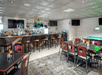 Restaurant interior with a bar, high stools, tables, chairs, pool table, and TVs. Ceiling and floor have patterned designs.
