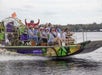 A group of people ride an airboat on a river, with some waving and smiling; the boat displays colorful graphics and tour company information.