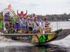 A group of people ride on an airboat with a guide at the controls, moving quickly across a body of water.