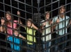 A family of five stands behind metal bars, smiling.