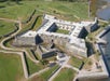 Aerial view of a star-shaped stone fortress surrounded by greenery and water.