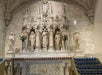 An alter with several gray stone statues and other carvings and rows of candles in front of them at St. Patrick's Cathedral.