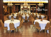 A banquet hall named "The Crystal Room" with round tables, white tablecloths, and chandeliers, set for an event.