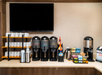 Coffee station with multiple dispensers labeled "Decaf", "Dark Roast", and "Regular Coffee", a selection of creamers, and stacks of cups and lids.