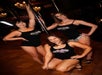 A group of three women in black tank top posed around a stripped pole for the photo at the Stripper 101 - Pole Dancing Class.