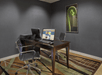 Office room with a dark wooden desk, two black office chairs, a computer and printer on the desk, and a framed image on the wall. The carpet has a geometric pattern.