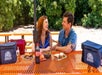 A man and woman sitting down at a bright orange picnic tables with their lunches spread out in front of them as part of the Sunburst Railbikes.