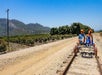 A man and woman wearing orange helmets while riding the Sunburst Railbikes and enjoying nature on a sunny day near Los Angeles.