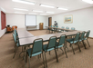 Meeting facility equipped with white screen projector, tables and chairs.