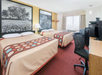 Two queen beds and a work desk inside a guest room.