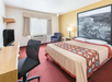 One king bed, a work desk and a flat-screen TV inside a guest room.