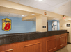 The brown and gray front desk at the Super 8 by Wyndham Mount Laurel with a light blue wall and a sign with their logo behind it.