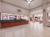 Spacious lobby with tiled floor, large reception desk, and seating area. Walls feature framed artwork, and large lights hang from the ceiling.