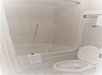 A shower-tub combo with a white curtain and a white toilet to the right of it in a bathroom at the Super 8 by Wyndham in Valdosta.