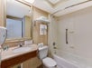 A bathroom with a bathtub, shower curtain, sink, mirror, toilet, and towel rack.