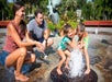 A mother and father watching their two children play in a small fountain with a statue of manatees behind them at ZooTampa.