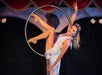 Woman wearing a white dress performs acrobatics on a hoop
