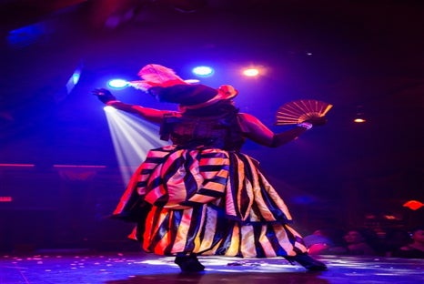 A woman with a hat and fan performs an act