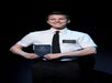 A person in a white shirt and tie holds a book titled "The Book of Mormon" while standing against a dark background.