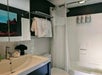 Modern bathroom with a sink, mirror cabinet, towel rack holding folded towels, a bathtub with a shower curtain, and wall-mounted soap dispensers.