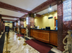 The long reception desk with polished wood and gold trim, marble floors, and small cherubs near the queue barriers.