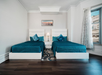 Two beds with a nightstand and lamp inside a room with city view.