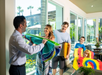 A family receiving colorful beach towels from a hotel staff member in a bright, modern lobby.
