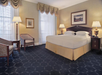 One king bed and an arm chair inside a guest room.