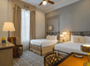 Guest room with two queen beds and well-lit work desk.
