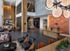 Spacious modern hotel lobby with wood accents, black tile flooring, a reception desk, comfortable seating, and decorative lighting.