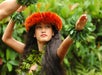 A beautiful hula dancer wearing an orange headdress with her hands up wearing bracelets and at The Feast at Mokapu Luau in Maui, Hawaii, USA