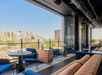 Rooftop lounge with modern seating overlooking an urban skyline on a clear day.
