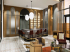 Modern bar interior with a marble counter, red chairs, and pendant lights. Sleek wooden walls and shelves with bottles create a stylish ambiance. Patterned floor tiles add texture.