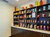 Shelves stocked with various snacks, candy, chips, drinks, and travel essentials in a hotel pantry area with dark wooden cabinets below.