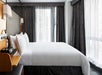 Guest room with one bed, alarm clock radio, floor-to-ceiling windows with black out drapes.